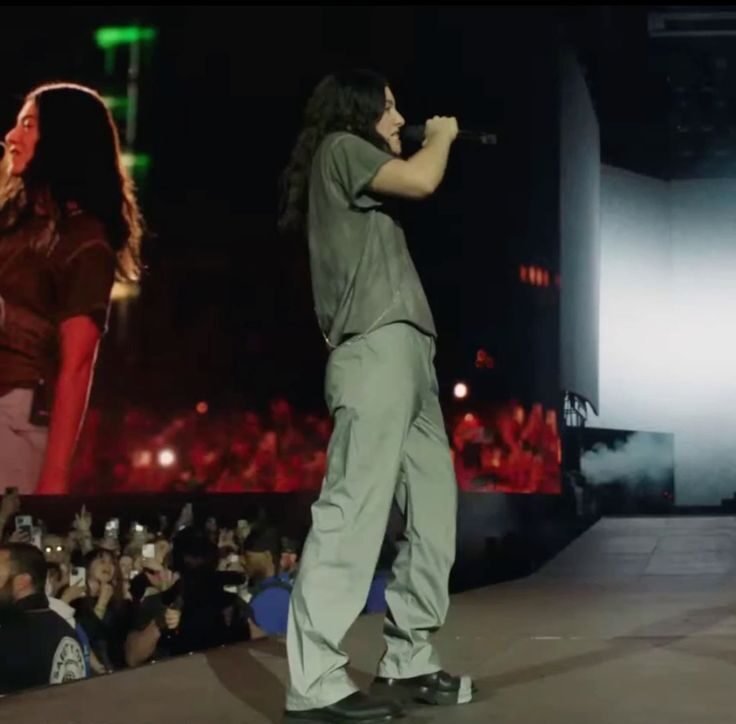 Lorde performing on stage at Coachella in a grey t-shirt and slouchy trousers — minimalist corpcore outfit