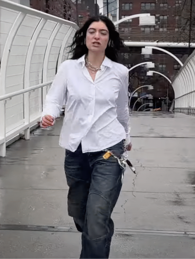 Lorde in a white untucked shirt with AirPods Max and formal shoes — quiet corpcore fashion style
