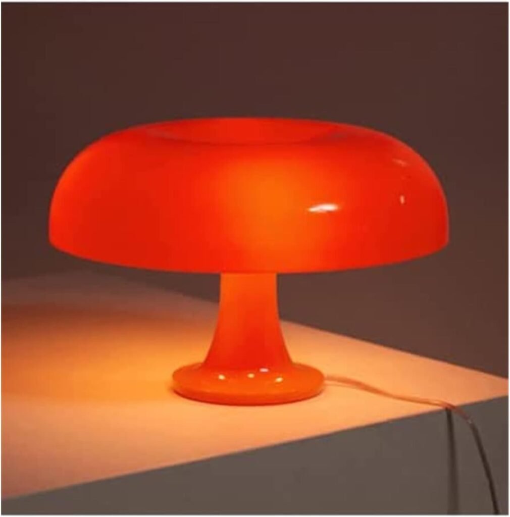Bright orange mushroom-shaped table lamp glowing on white surface in a dim room