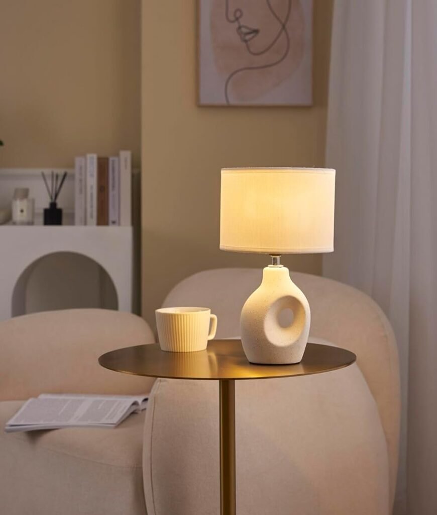 stylish table lamps - Cream ceramic cut-out lamp on side table next to curved beige armchair