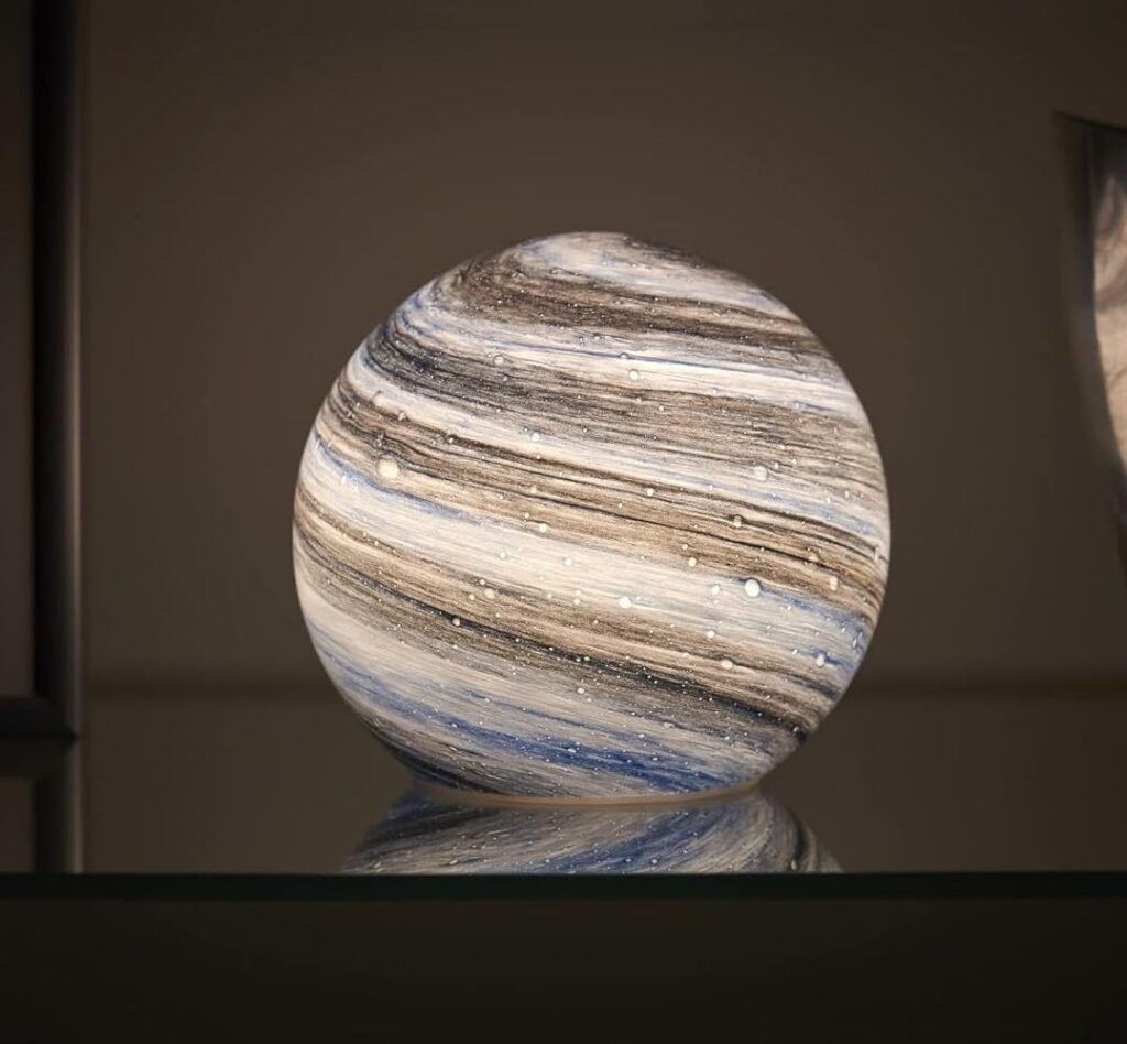 Round marbled glass orb table lamp with soft glow on glass shelf