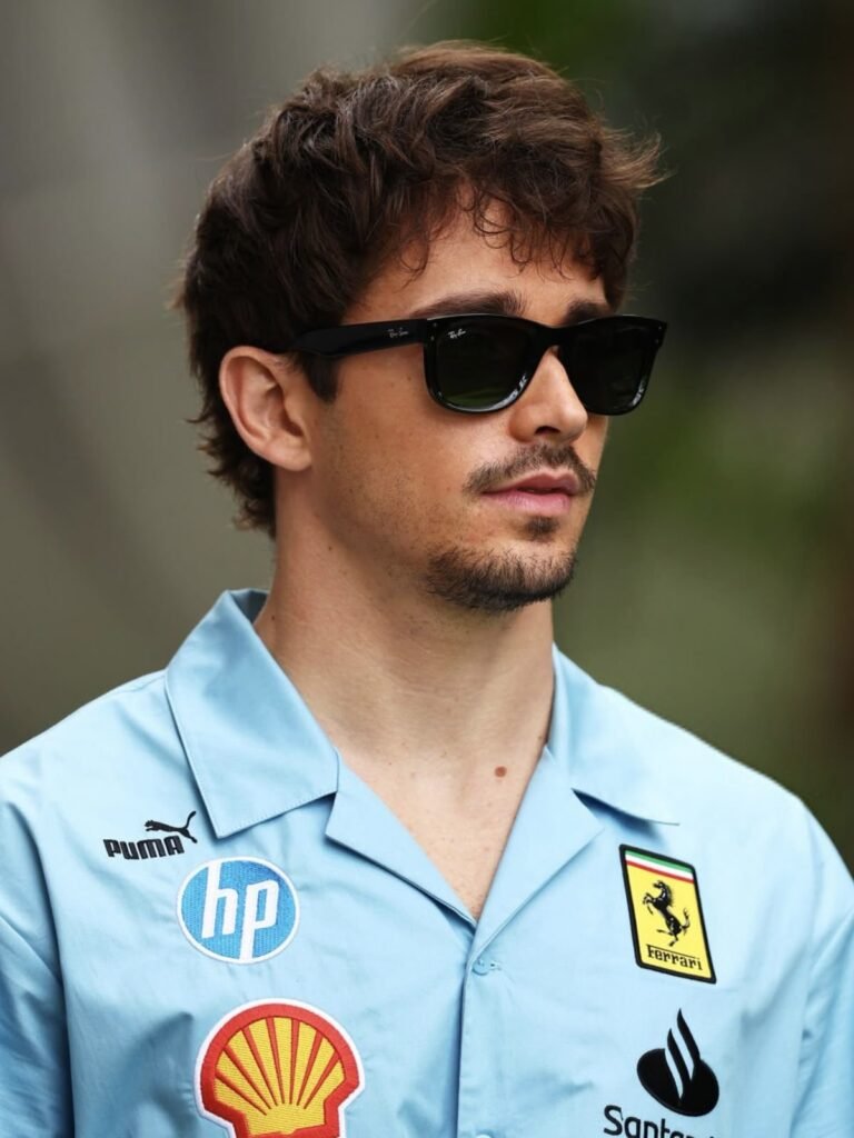 Spring to Summer Wardrobe Essentials - Man wearing black Ray-Ban Wayfarer sunglasses and light blue Ferrari shirt outdoors
