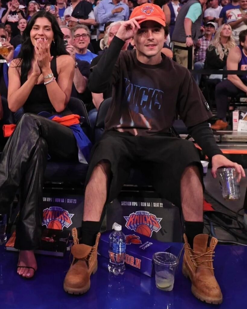 This Timothée Chalamet courtside outfit layers a thermal long sleeve under a washed-out oversized tee with baggy jorts and wheat Timberlands. It’s the kind of look that feels thrown together but lands perfectly. In this post, we found real items you can use to copy the whole fit — including the dad cap. If you want a low-effort, high-confidence summer look with Chalamet’s vibe, this is the one to try.