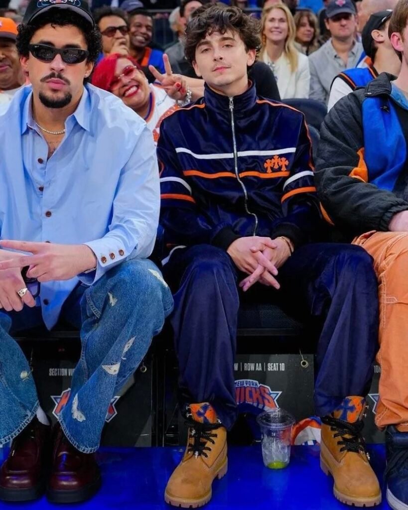 Timothée Chalamet’s courtside velour look brings together a navy tracksuit and Knicks-colored Timberlands for a fit that’s loud and luxe at the same time. In this post, we matched the vibe with affordable picks and added a cross pendant chain to finish the Chrome Hearts feel. It’s one of his most iconic game-day looks, and surprisingly easy to recreate with a few sharp choices and the right layering.
