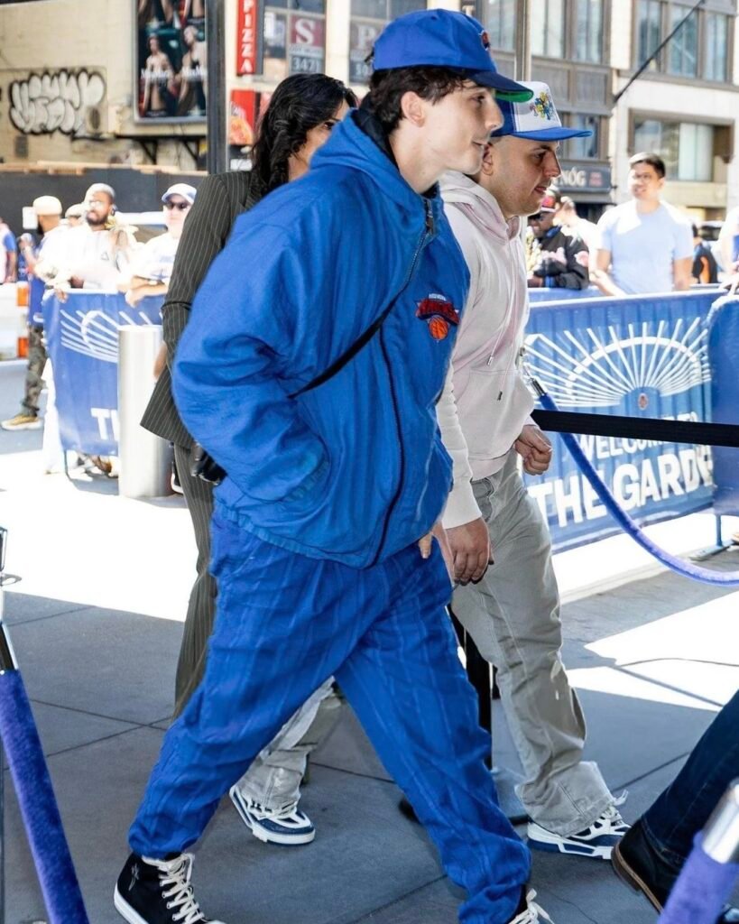 Probably the most wearable of all Timothée Chalamet’s Knicks fits. This one’s built from a washed hoodie jacket, wide-leg pinstripe trousers, black high-top Chucks, and a clean crossbody bag. We found the exact pieces you’ll need to recreate the full fit — simple but put together. If you want to ease into Timmy’s style without going full velour or camo, this one’s the entry point.