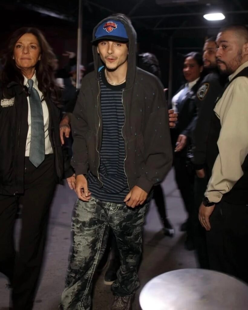 This Timothée Chalamet look feels like a post-game tunnel fit — faded hoodie, navy striped tee, standout jeans, and a fitted cap. It’s a throwback to mid-2000s energy but still feels current. In this post, we pulled together the exact style of camo-textured jeans and layering pieces to bring this look together without going overboard. It’s casual, confident, and one of his most distinctive fits.