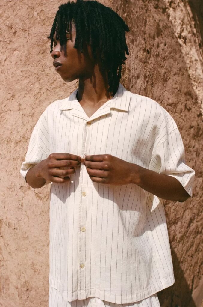 Model in a short sleeve cream linen shirt with vertical stripes, ideal for summer. men's summer shirts