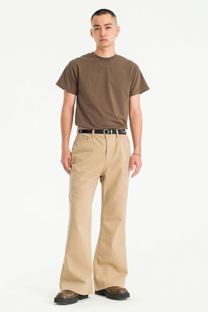 A model in beige wide-leg twill trousers from Olive Clothing, paired with a brown tee and boots.