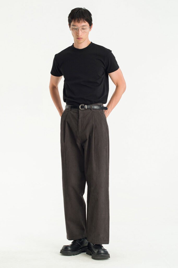 A model wears charcoal wide-leg corduroy trousers by Olive Clothing, styled with a black tee.