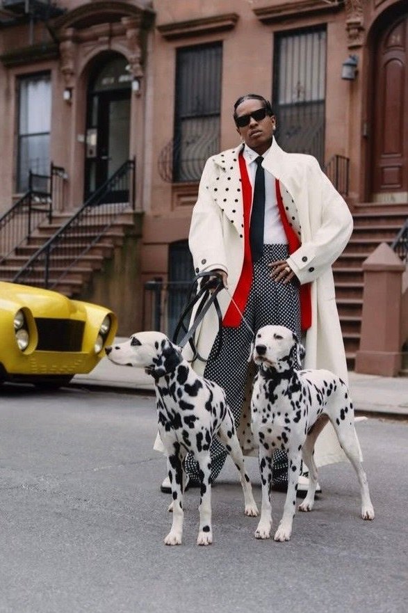 ASAP Rocky walks two dalmatians in a long coat with polka-dot trousers and red accents.