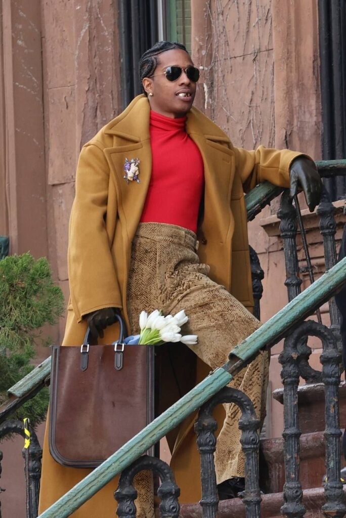 ASAP Rocky steps out in a camel overcoat, red turtleneck, and leather gloves, holding tulips.