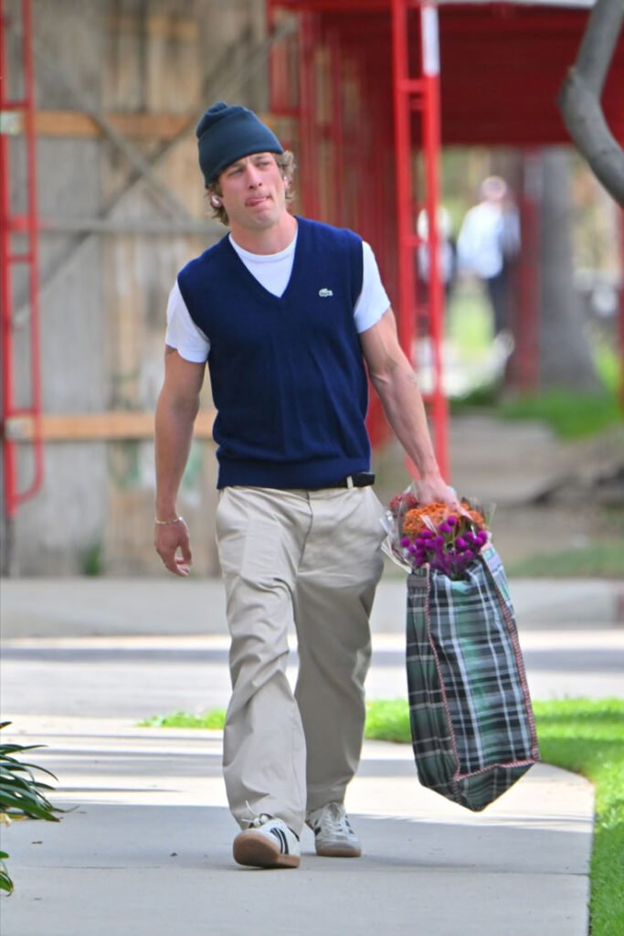 Jeremy Allen White layering a navy knit sweater vest with smart-casual separates.