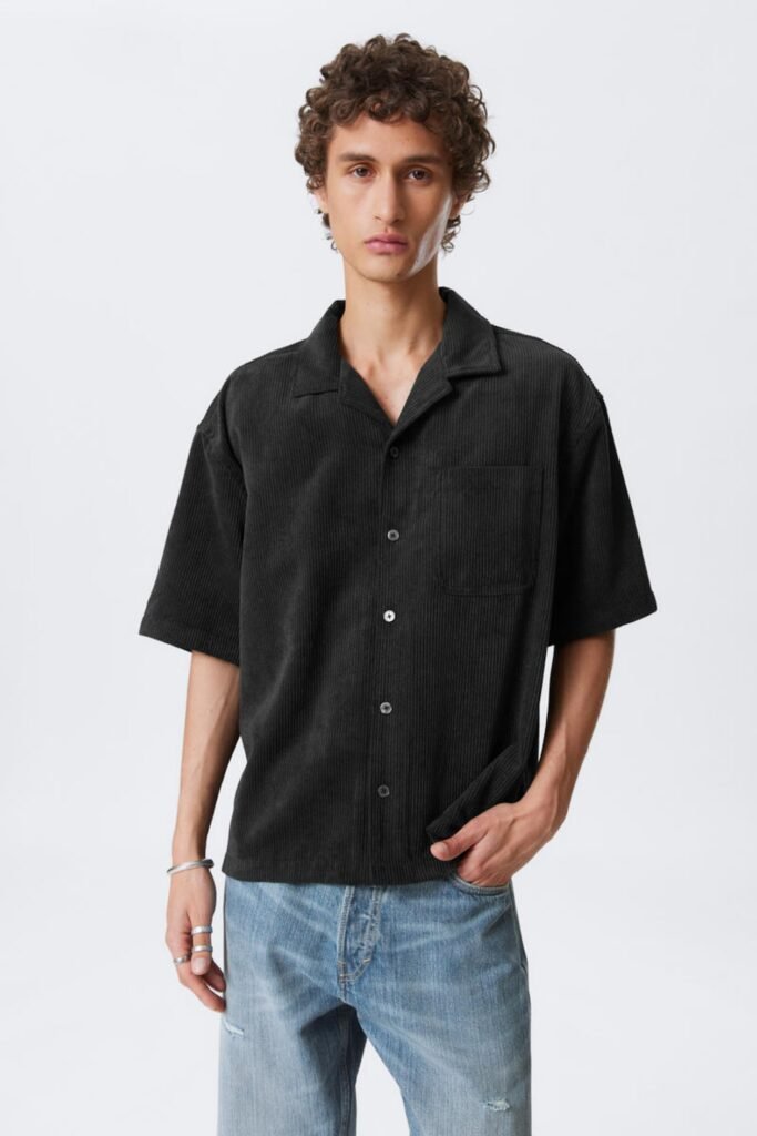 Model wearing a black corduroy short sleeve resort shirt styled with jeans.