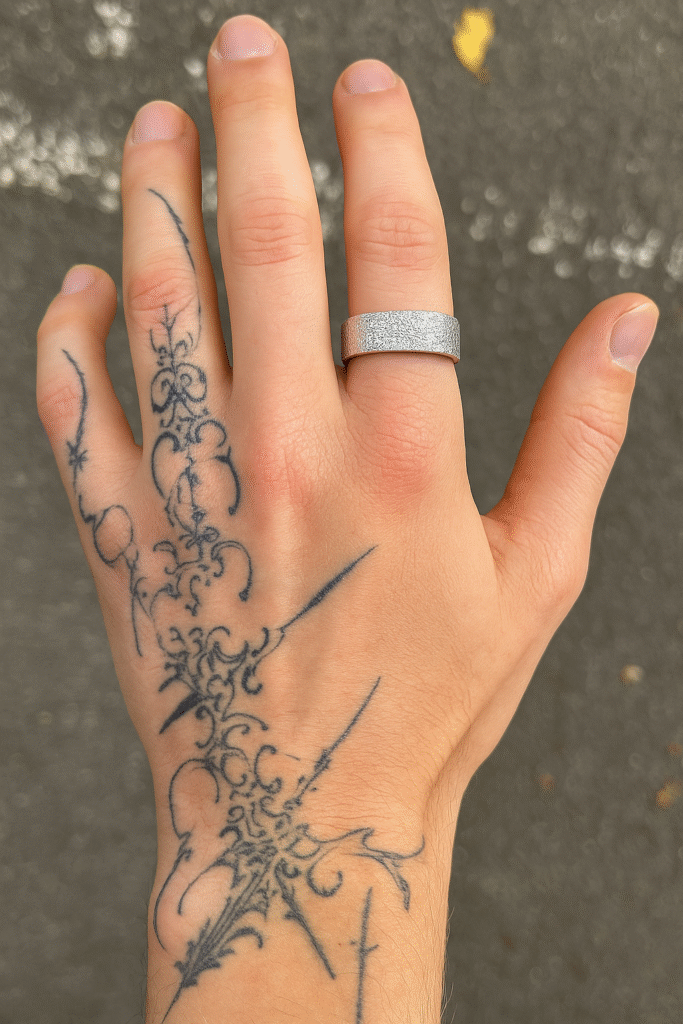 A tattooed man’s hand wearing a slim sterling silver ring with frosted, cracked texture detailing.