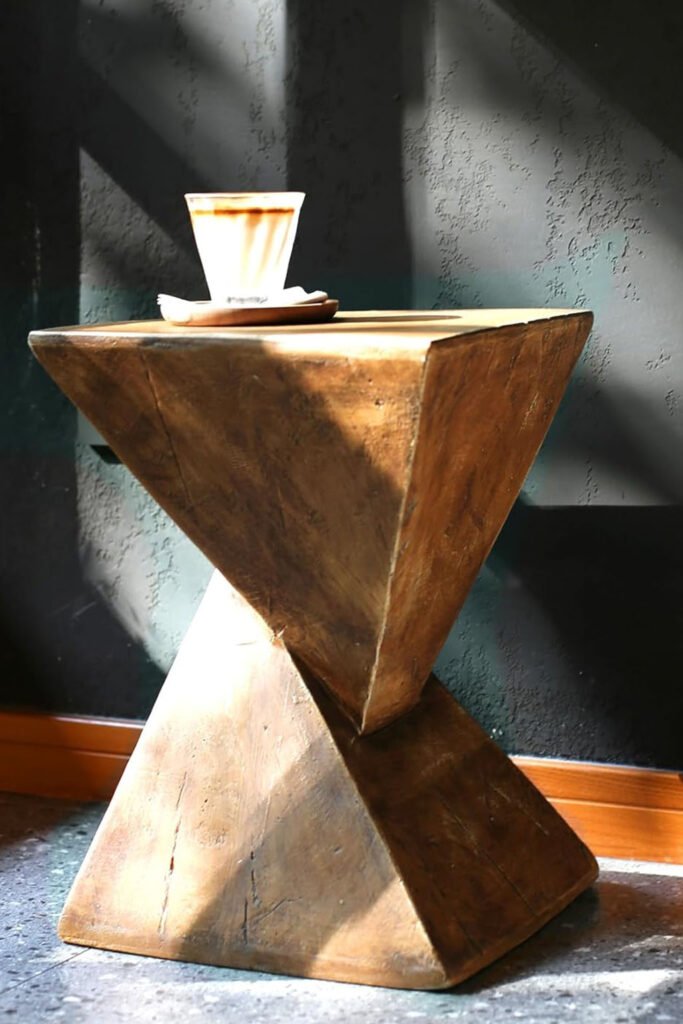 Angular stylish side tables with a brutalist silhouette and modern sculptural design, sunlight casting shadows across its surface.