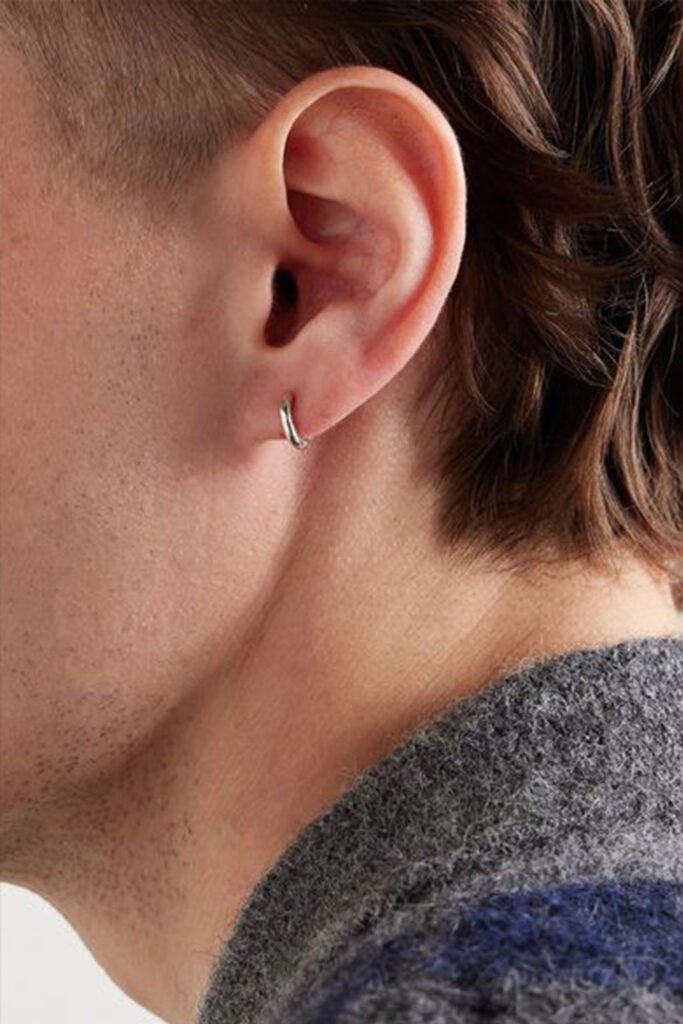 Close-up of small sterling silver sleeper hoop earring on a man