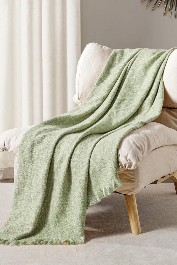 Light sage green woven throw blanket draped over a beige chair.